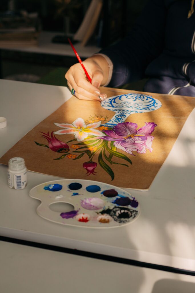 A floral painting in progress with vibrant colors on a wooden canvas, expressive and creative.